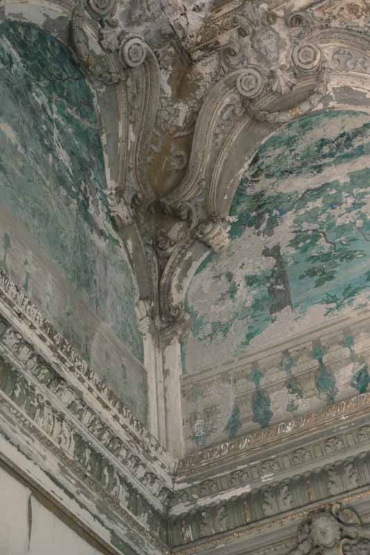 Close-up shot of a corner decorated with ruined stucco and water infiltration marks on a wall.